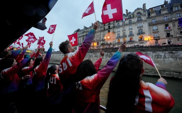 Foto Kontingen Swiss menyapa para penonton dalam parade opening ceremony Olimpiade Paris 2024 di sungai Seine (27/7/2024) (Foto: X @Paris2024)