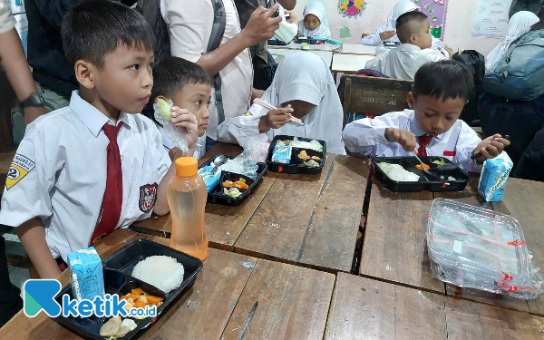 Foto Para siswa SDN Klampis Ngasem III terlihat lahap menikmati makan siang yang disajikan. (Foto: Husni Habib/Ketik.co.id)