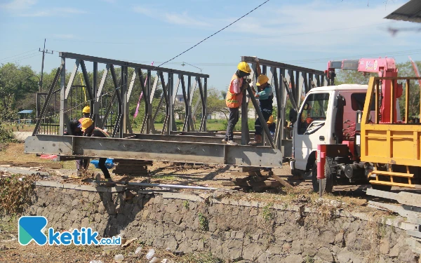 Foto Para pekerja merakit jembatan Bailey di sisi utara Dam Kedungpeluk, Kecamatan Candi, Sidoarjo, pada Sabtu (3/8/2024). (Foto: Fathur Roziq/Ketik.co.id)