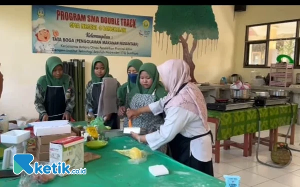 Foto Guru Pembimbing Double Track Tata Boga SMAN 4 Bangkalan, Fika Febrianti bersama para siswa membuat kue Bolu Lapis Kukus Suramadu. (Foto: Siti Zahira/Ketik.co.id)