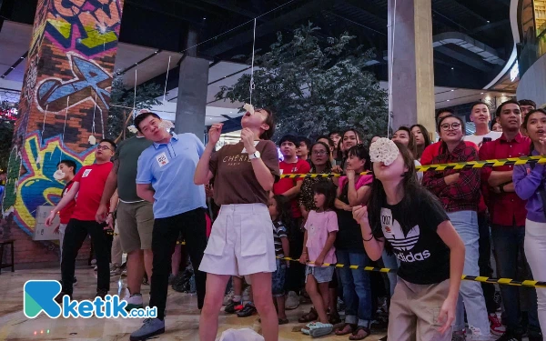 Foto Peserta lomba makan kerupuk ini berusaha untuk habiskan kerupuknya, Minggu (18/8/2024). (Foto: Khaesar/Ketik.co.id)