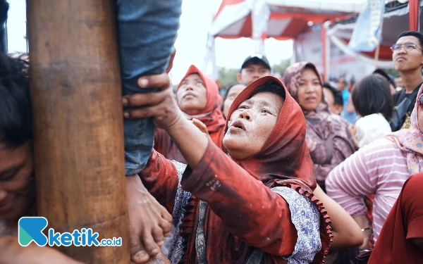 Foto Sejumlah penonton bahu membahu memberikan bantuan kepada para peserta panjat pinang. Foto: Wisnu Akbar Prabowo