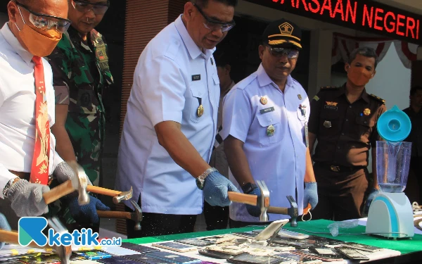 Foto Barang bukti kejahatan berupa telepon genggam dihancurkan dengan dipukul palu secara bersama-sama.  (Foto: Fathur Roziq/Ketik.co.id)