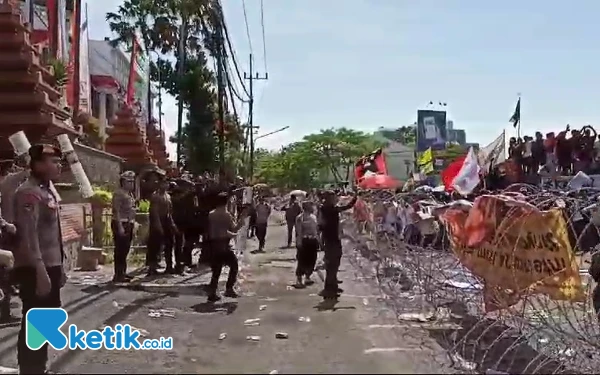 Foto Polisi berusaha meredam aksi lempar botol dari massa yang berdemo di DPRD Jatim, Jumat, 23 Agustus 2024. (Foto: Khaesar/Ketik.co.id)