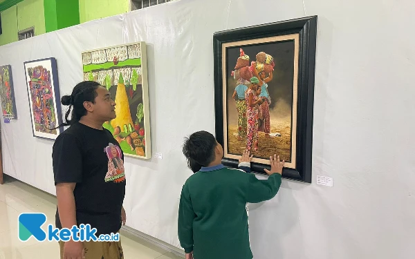 Foto Danni Sekretaris Lesbumi Kecamatan Ngantang bersama pengunjung menyaksikan pameran seni lukis di gedung MWC NU Ngantang. (Foto: Dok. Danni)