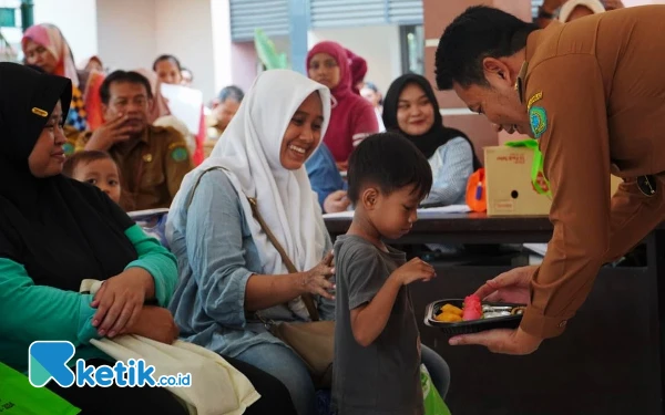 Foto Ibu-ibu tampak senang saat Plt Bupati Sidoarjo H Subandi memberikan kue untuk anak-anak mereka. (Foto: Dinas Kominfo Sidoarjo)