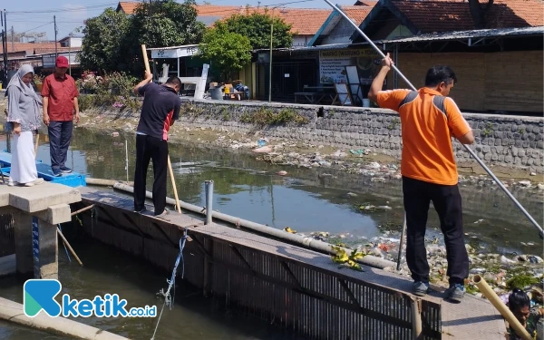 Foto Tim Perumda Delta Tirta Sidoarjo membersihkan sampah di Kali Pelayaran. Sebagian harus turun ke sungai karena banyaknya sampah. (Foto: Istimewa)