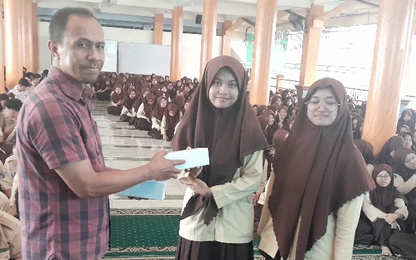 Foto Sumarno memberikan cinderamata kepada 2 siswa pengelola koran sekolah. (Dea for Ketik.co.id)