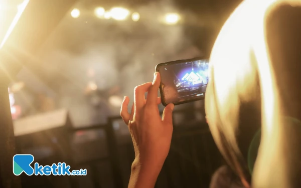 Foto Salah satu pengunjung Festival Jazz Internasional Suara Musi tengah mengabadikan penampilan musisi jazz menggunakan kamera ponselnya, Sabtu 30 November 2024. (Foto: Wisnu Akbar Prabowo/Ketik.co.id)