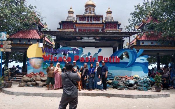 Foto Pengunjung berswafoto bersama keluarga di wisata Pasir Putih Dalegan