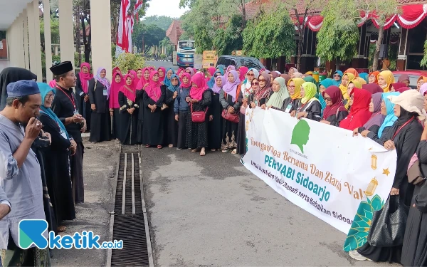 Foto Sebelum berangkat ziarah, rombongan Perwabi Sidoarjo berdoa bersama di halaman Pendopo Delta Wibawa. Dipimpin Sujani sebagai ketua perkumpulan para janda atau single parent di Sidoarjo. (Foto: Fathur Roziq/Ketik.co.id)