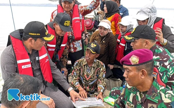 Foto Plt Bupati Sidoarjo Subandi mengecek peta lokasi yang dibawa perangkat Desa Segoro Tambak saat naik perahu menuju lokasi HGB di laut. (Foto: Mashud/Kominfo Sidoarjo)