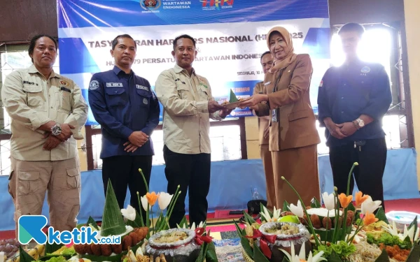 Foto Kepala Dinas Kominfo Sidoarjo menerima potongan tumpeng dari Ketua PWI Sidoarjo Mustain. (Foto: PWI Sidoarjo)