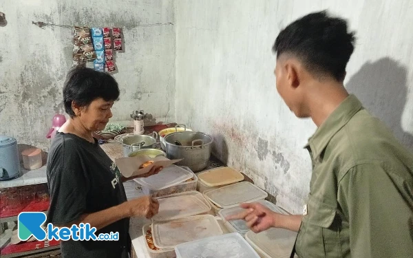 Foto Mak Widi tengah memaparkan lauk pauk yang dijualnya kepada pembeli. (Foto: Al Ahmadi/Ketik.co.id)