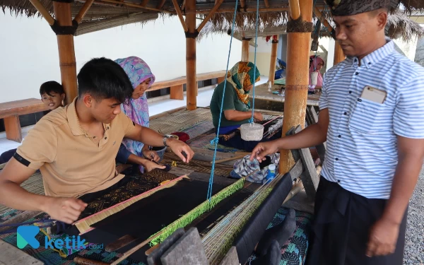 Foto Mario Aji mencoba menenun kain songket Lombok didampingi pelatih. (Foto: Samsul Hadi Mustofa/Ketik.co.id)