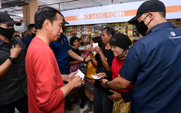 Foto Jokowi menyerahkan amplop THR untuk pedagang pasar. (Foto: BPMI)