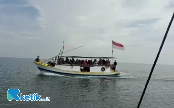 Foto Wisatawan naik kapal motor mengarungi lautan yang jernih dengan warna kehijauan. (Foto: Ocha for Ketik.co.id)