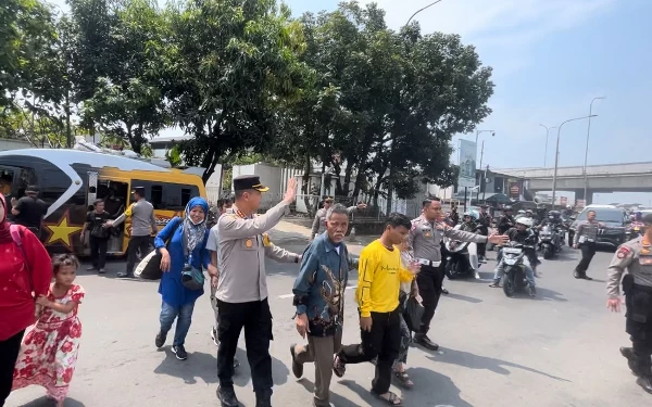 Foto Kapolresta Bandung Kombes Pol Kusworo Wibowo membantu pemudik menyeberang jalan di jalur mudik Cileunyi Kab Bandung, Minggu (30/4/23). (Foto: Humas Polresta)