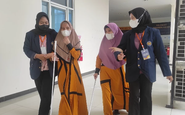 Foto Peserta kembar disabilitas didampingi oleh pendamping untuk mengikuti UTBK di Unesa, Rabu (10/5/2023). (Foto : Humas Unesa)