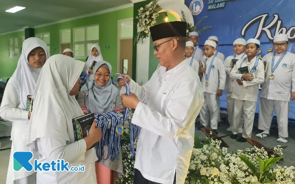 Foto Hanafi Kabid Keagamaan YPIA Jatim saat mengalungkan medali untuk siswa - siswi yang selesai Khotmul Quran.