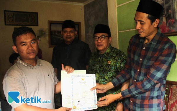 Foto Satriya (kiri) menerima ijazah Mts dari Baznas disaksikan H Usman di rumahnya Desa Tulangan, Kecamatan Tulangan, Kabupaten Sidoarjo, Kamis (15/6/2023). (foto: Fathur Roziq/Ketik.co.id)