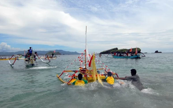 Foto Larung sesaji mengantar makanan ke tengah laut dan kerap dijadikan rebutan warga maupun pengunjung. (Foto: Disbudpar Jember).