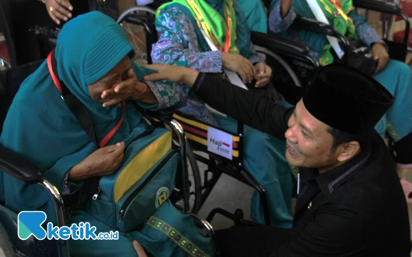 Foto Wabup Subandi menyemangati seorang CJH yang naik kursi roda agar tetap semangat menunaikan ibadah haji. Hati-hati jaga kesehatan.