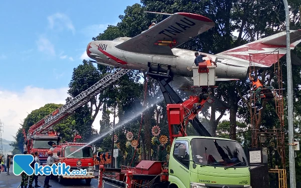 Foto Anggota Damkar Kota Batu menyemprot air ke monumen pesawat MiG 17 Fresco di Jalan Sultan Agung Kota Batu, Kamis (13/7/2023). (Foto: Sholeh/ketik.co.id)