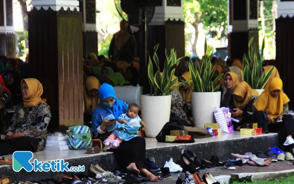 Foto Seorang peserta pertemuan kader kesehatan menggendong buah hatinya sambil mengikuti acara di Pendapa Delta Wibawa Jumat pagi (28/7/2023). (Foto: Fathur Roziq/Ketik.co.id)