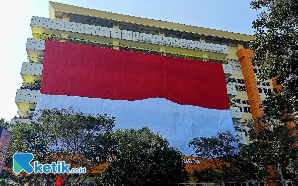 Foto Bendera merah putih raksasa membentang di gedung RSSA Malang (foto: Lutfia/ketik.co.id)