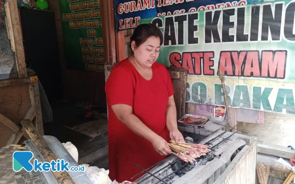 Foto Mbak Diyah sedang membakar Sate Kelinci di Warungnya di Kawasan wisata payung 2 Kota Batu. (Foto: Sholeh/ketik.co.id)