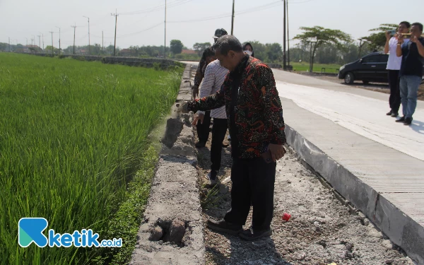 Foto Wakil Ketua Komisi C DPRD Sidoarjo Anang Siswandoko terlihat memegang dan meremas serpihan beton tanggul penahan tanah (TPT) di proyek benonisasi jalan desa di Mliriprowo, Tarik, Sidoarjo. (Foto: Fathur Roziq/Ketik.co.id)