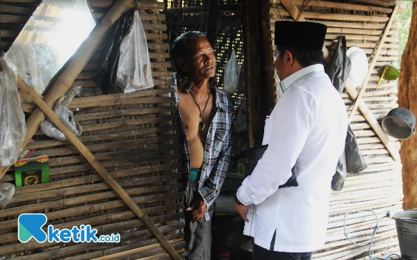 Foto Legislator DPRD Sidoarjo Dhamroni Chudlori disambut Nurcholis di depan pintu gubuknya pada Kamis (21/9/2023).  (Foto: Fathur Roziq/Ketik.co.id)