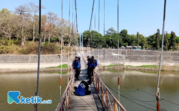 Foto Pengunjung sedang foto di jembatan gantung ikonik di Bendungan Selorejo Kecamatan Ngantang Kabupaten Malang. (Foto: Sholeh/ketik.co.id)