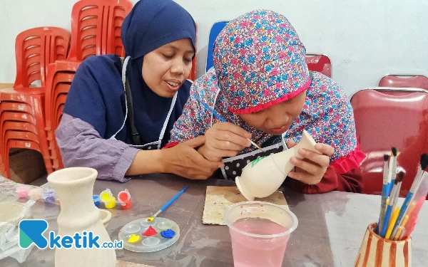 Foto Pipit, difabel netra yang didampingi kakaknya saat melukis di vas bunga. (Foto: Lutfia/Ketik.co.id)