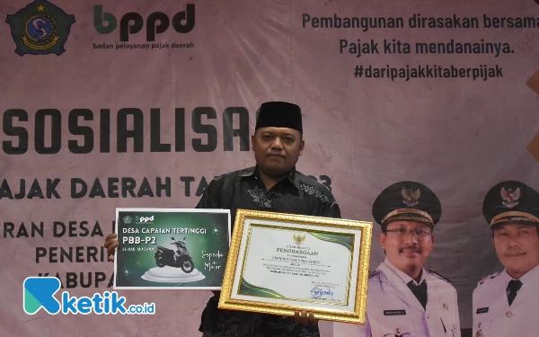 Foto Sekretaris Desa Keret, Krembung, Rusdin Hari Setiawan, menerima penghargaan dari Bupati Sidoarjo sebagai Desa dengan Capaian Penerimaan PBB-P2 Terbaik se-Kabupaten Sidoarjo Tahun 2023 Kategori Perdesaan.  (Foto: BPPD Sidoarjo)