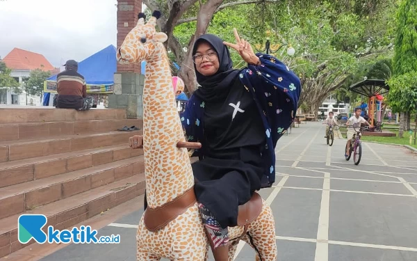 Foto Seorang pengunjung yang mencoba tunggangan yang berbentuk hewan jerapah. (Foto: Al Ahmadi/Ketik.co.id)