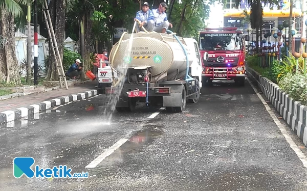 Foto Petugas menyiramkan air tangki demi membersihkan Jalan Cokronegoro dari tumpukan sampah yang dibuang pengunjuk rasa pada Rabu (20/12/2024). (Foto: Istimewa)