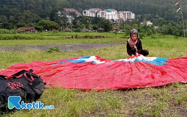 Foto Naila Salwa Quyun sedang melipat parasut usai mendarat di Landing Paralayang Kelurahan Songgokerto Kota Batu. (Foto: Sholeh/ketik.co.id)