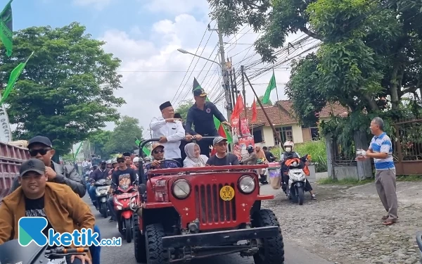 Foto Sembari menyapa masyarakat disepanjang perjalanan Harda Kiswaya terus berdiri di atas Jeep. (Foto: Teguh Ariffianto / Ketik.co.id)