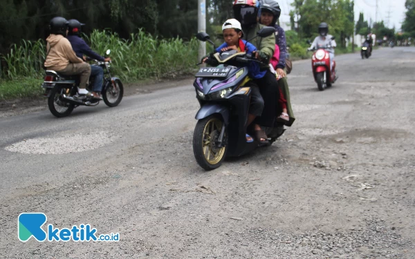 Foto Pengendara sepeda motor melewati lajur berlawanan di Jalan Sawunggaling, Kletek, Taman, Sidoarjo, demi menghindari lubang jalan pada Minggu (17/3/2024). (Foto: Fathur Roziq/Ketik.co.id)