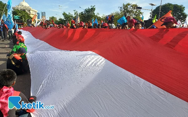 Foto Aksi masa buruh membentangkan bendera merah putih saat melakukan aksi demo, Rabu (1/5/2024). (Foto: Khaesar/Ketik.co.id)