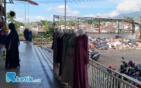 Foto Pedagang pakaian yang berdekatan dengan Tumpukan sampah di Pasar Induk Among Tani Kota Batu. (Foto: Sholeh/Ketik.co.id)