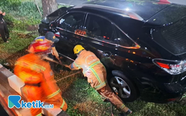 Foto Petugas pemadam kebakaran mencoba evakuasi mobil yang tabrak pohon di Jalan HR Muhammad Surabaya, Jumat (14/6/2024). (Foto: Comment Canter 112)