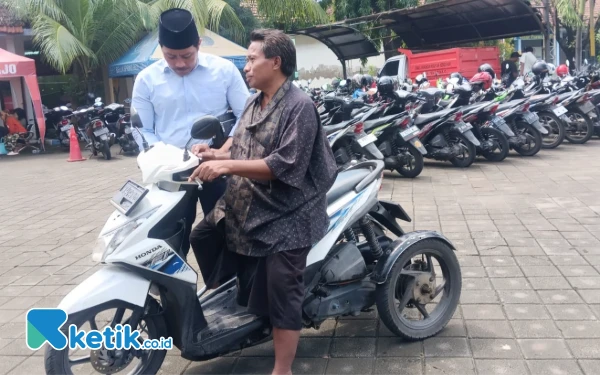 Foto Ketua Komisi D DPRD Sidoarjo Dhamroni Chudlori berbincang dengan Sukardi yang baru tiba dengan sepeda motor roda tiga. (Foto: Fathur Roziq/Ketik.co.id)