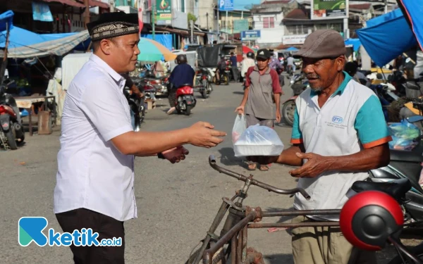 Foto Kasat Reskrim Polres Abdya, Iptu Wahyudi menyerahkan paket takjil untuk salah satu pengendara becak di Pasar Blangpidie, Rabu, 15 Maret 2025. (Foto: Cutbang Ampon/Ketik.co.id)