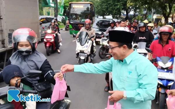 Foto Anggota Fraksi PKB DPRD Sidoarjo H Usman MKes mengulurkan takjil gratis ke seorang pengendara. (Foto: Fathur Roziq/Ketik.co.id)