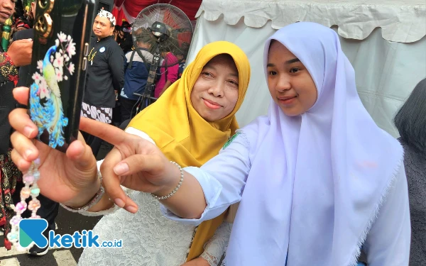 Foto Penyanyi sekaligus pesinden Niken Salindry (kanan) berswafoto bersama penggemarnya usai tampil di panggung berseragam SMA dan wajah tanpa make up di sela  Peringatan Hari Pendidikan Nasional 2025 di Gedung Negara Grahadi Jalan Gubernur Suryo Surabaya, Jumat, 2 Mei 2025. (Foto: Fiqih Arfani/Ketik.co.id)
