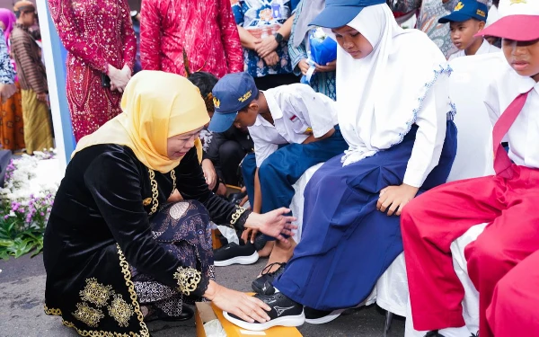 Foto Gubernur Jatim Khofifah Indar Parawansa (kiri) memasangkan sepatu kepada perwakilan siswi sela upacara memperingati Hari Pendidikan Nasional (Hardiknas) 2025 di Gedung Negara Grahadi di Surabaya, Jumat, 2 Mei 2025. (Foto Biro Adpim Pemprov Jatim)