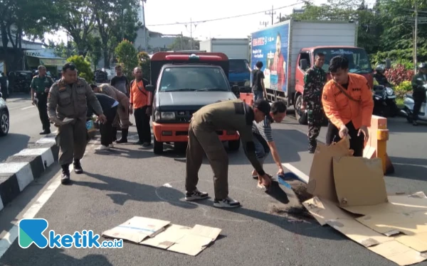 Foto Petugas Satpol PP dan BPBD Surabaya menutupi kardus dan tanah tempat tewasnya Wisnoe di Jalan Kalirungkut Surabaya, Selasa, 20 Mei 2025. (Foto: Khaesar/Ketik.co.id)